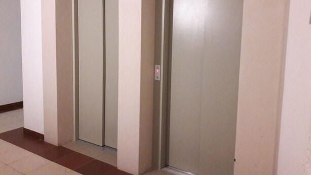 Un couloir avec deux portes de monte-charge fermées et un sol carrelé.