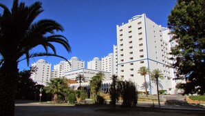 Un complexe hôtelier moderne composé de plusieurs immeubles de grande hauteur, de palmiers et surplombé d’un ciel d’un bleu éclatant.