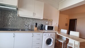 Une cuisine compacte équipée d’un lave-linge, d’un four à micro-ondes et d’un évier.