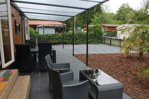Ein Terrassenbereich im Freien mit Korbmöbeln und einer überdachten Sitzgelegenheit.