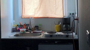 A compact kitchen with a window, sink, and a small refrigerator.