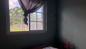 A room with a window, a table with papers, and a chair.