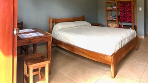 A bedroom with a wooden bed, a small wooden desk, and a chair.