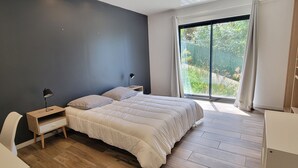 A bedroom with a large bed, a bedside table, a lamp, and a view of greenery through a window. - House 5p with garden in the heart of Saint-Raphaël (Saint-Raphaël)