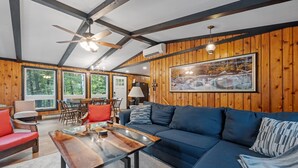 A cozy living room with a blue sofa, red and blue chairs, a wooden coffee table, and a ceiling fan.