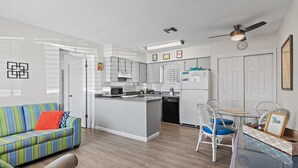 Een moderne keuken met witte kasten, een centraal eiland en een eetgedeelte met witte stoelen.