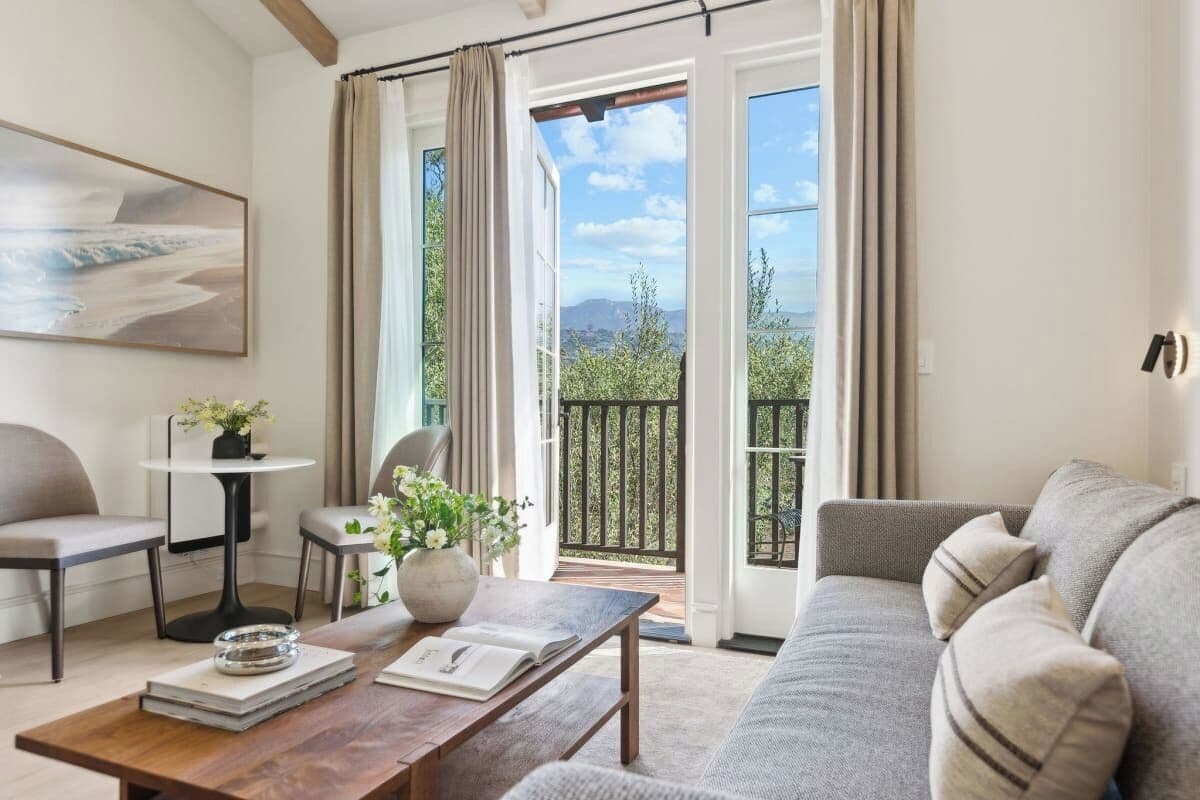 A living room with a sofa, a coffee table, and a view of a balcony with outdoor furniture.