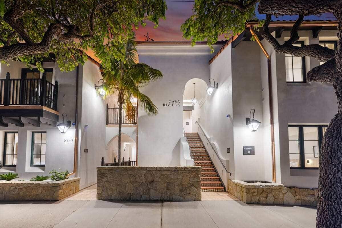 A modern hotel interior with a central staircase, stone planters, and a sign reading "CASA RIVIERA".