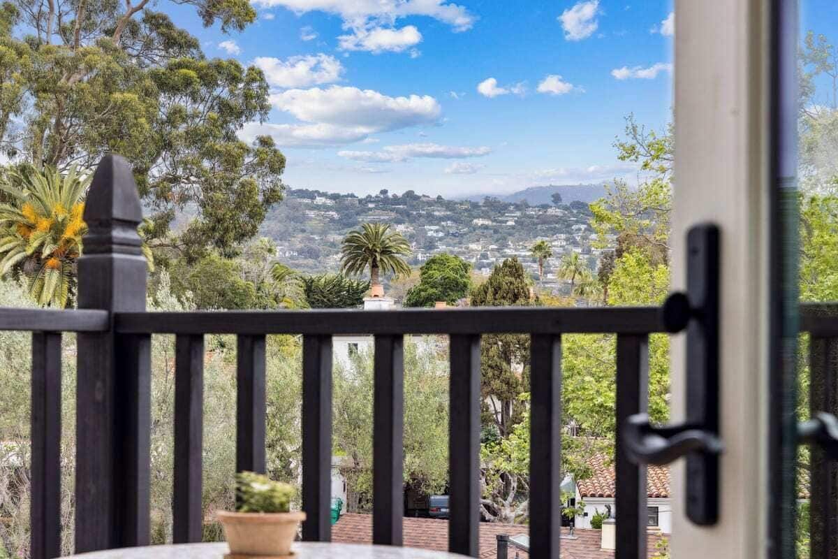 A balcony with a view of a cityscape, including trees and buildings.