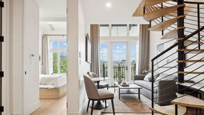 A spacious living area with a modern staircase, a dining table, and a sofa.
