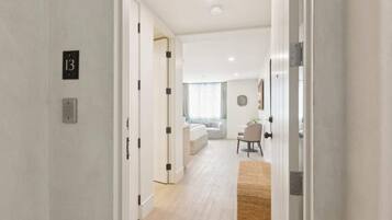 Une chambre d’hôtel moderne au design minimaliste, dotée d’un plancher en bois, d’un canapé, d’une table à manger et d’un petit tapis.
