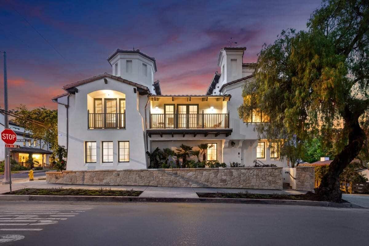A two-story house with a stone facade, large windows, and a balcony.