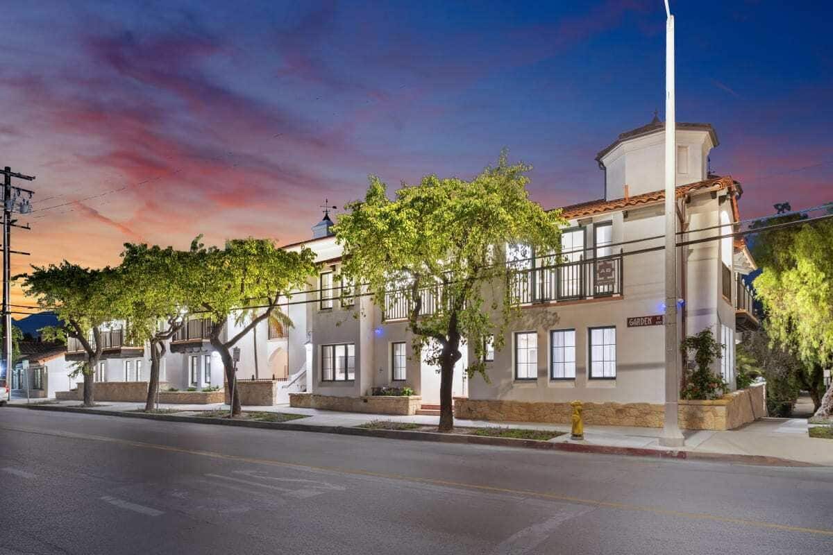 A two-story building with a white facade, multiple windows, and a visible sign that reads "GARDEN."