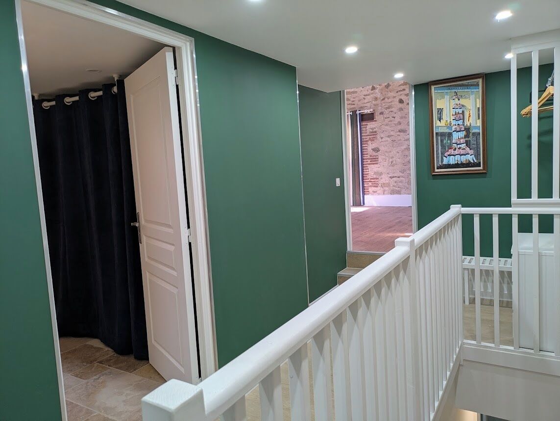 A hallway with green walls, a white door, and a staircase with a white railing.