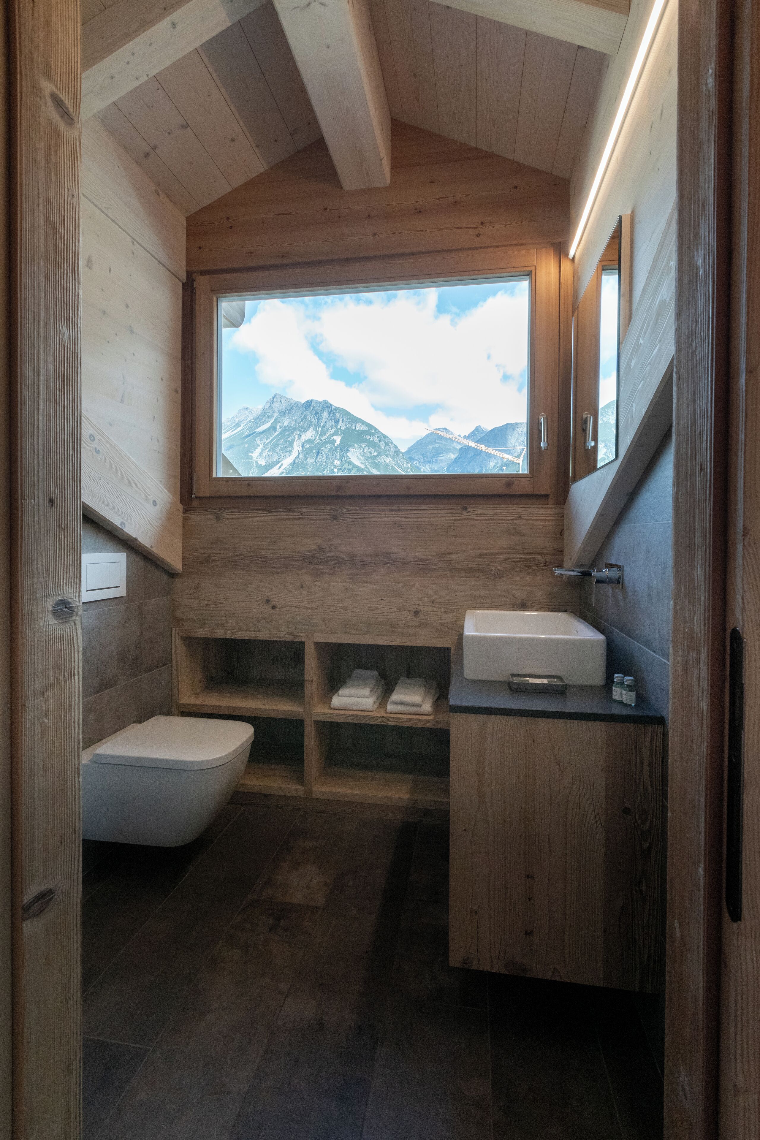 Baño de cabaña de madera con inodoro, lavabo y repisas.