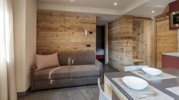 Una sala de estar moderna con un sofá marrón, una mesa de comedor con platos y cubiertos blancos, y paneles de pared de madera.
