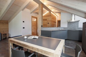 Una cucina moderna con soffitto in legno, un piano di lavoro in granito e mobili grigi.