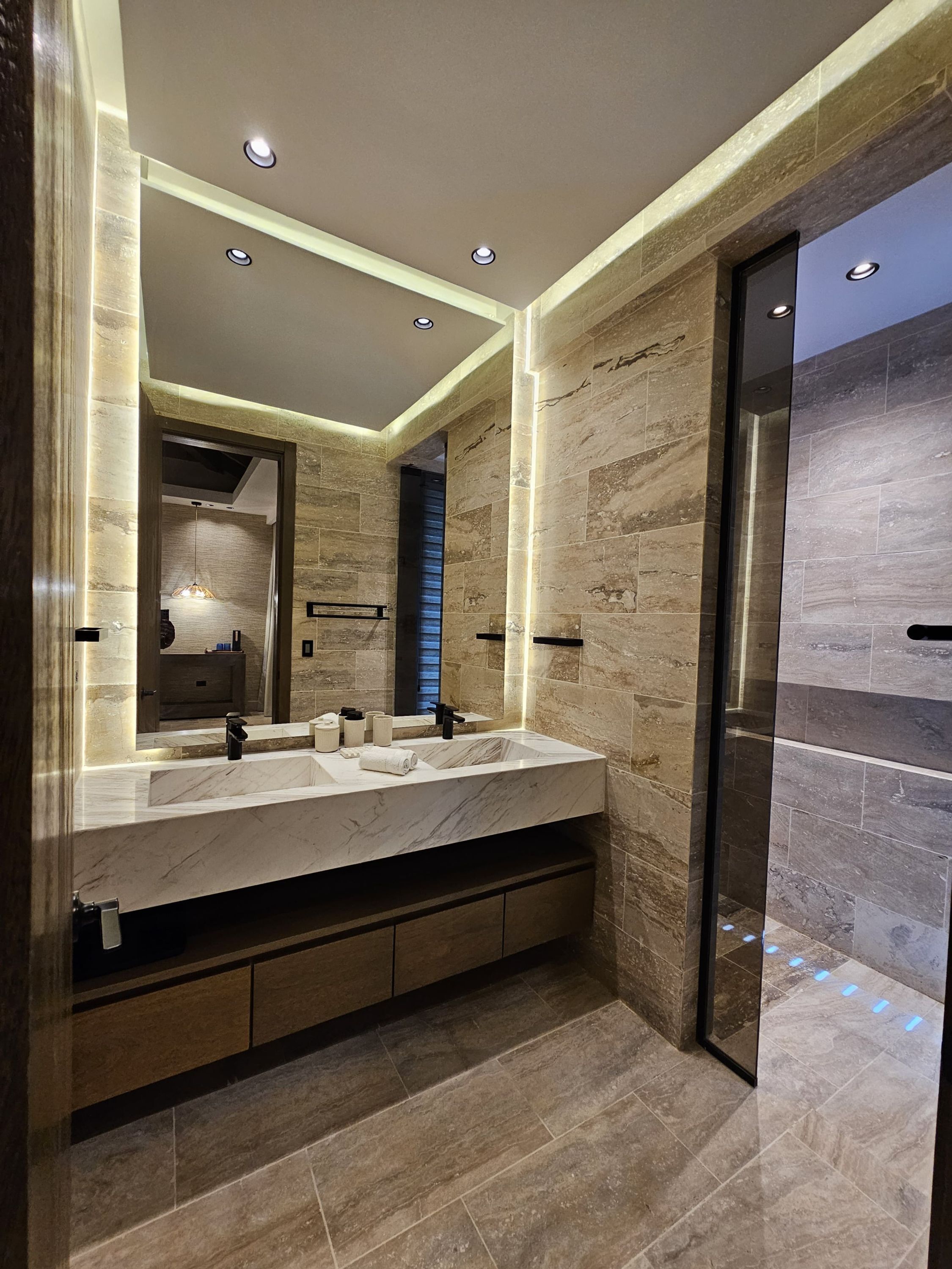 Un baño moderno con lavamanos doble, encimeras de mármol y un espejo grande.