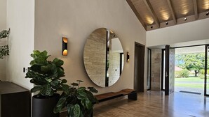 A spacious lobby with a large mirror, potted plants, and a bench.