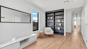 Un couloir moderne avec une grande bibliothèque, un coin salon avec un fauteuil et un banc intégré.