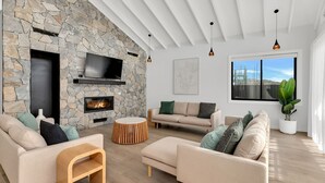 Un salon moderne doté d’une cheminée en pierre, de sièges confortables et d’une grande fenêtre offrant une vue imprenable.