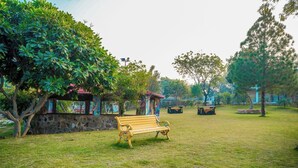 A park with a wooden bench, stone wall, and a gazebo with colorful murals. -  Royal green  Spacious farmhouse with 8 bedrooms and AC, WiFi in charming Sohna (Sohna)