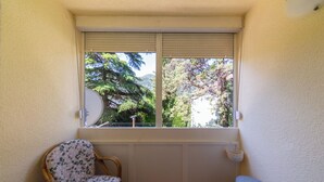A small balcony with a window, two wicker chairs, a small stool, and a white wall. - Lovely 2 Bdr Apartment in Heart of Kotor (Dobrota)