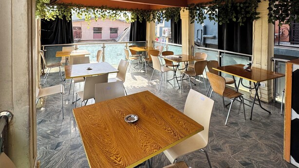 An indoor dining area with wooden tables and chairs, a ceiling fan, and a view of the street outside. - Sparcles Hotel and Lounge  (Lagos)