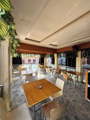 An indoor dining area with wooden tables and chairs, a ceiling fan, and a view of the street outside. - Sparcles Hotel and Lounge  (Lagos)