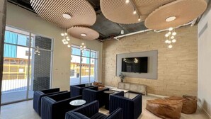 Un espace de détente moderne, doté de sièges confortables, d’un téléviseur à écran plat et d’une grande fenêtre offrant une vue sur l’extérieur.