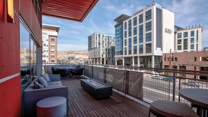 Une terrasse sur le toit, dotée d’un espace extérieur aménagé, d’un foyer et offrant une vue sur les bâtiments environnants.