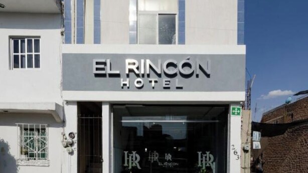 The exterior of El Rincon Hotel with a modern design, featuring a prominent entrance and a clear sign.