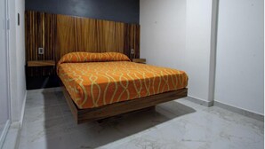 A bedroom with a bed, wooden headboard, and a white wall.