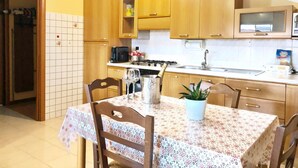 A kitchen with wooden cabinets, a stove, a microwave, and a dining table with chairs.