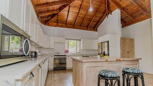 A spacious kitchen with white cabinets, a wooden ceiling, and a large island with stools. - Large Seaview 3 Bedroom Villa with Private Pool, Terrace & Parking (Discovery Bay)