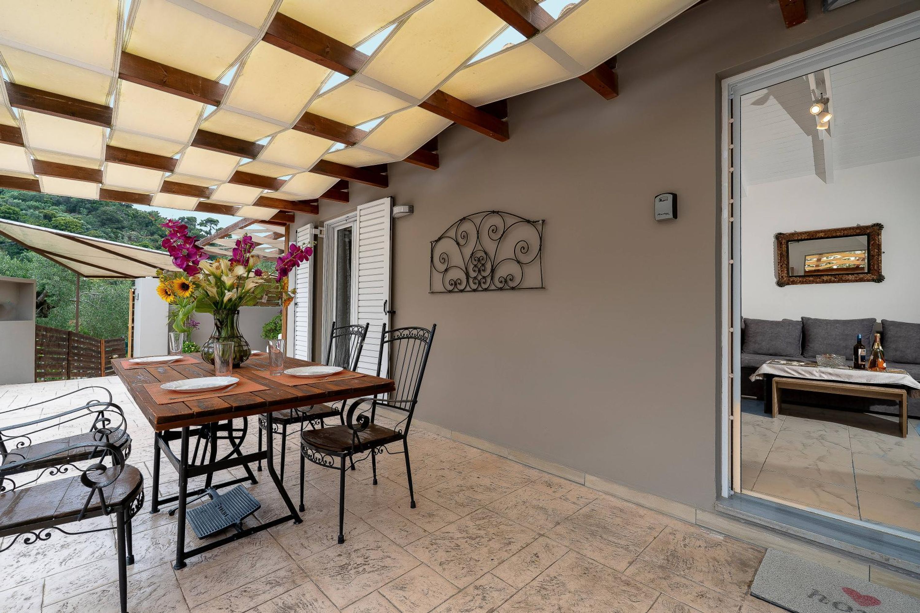 A dining area with a wooden table and chairs, a vase with flowers, and a decorative metal piece on the wall.