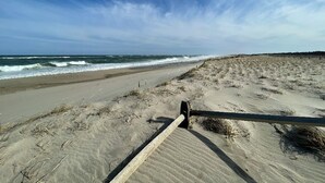 Una playa con una barandilla de madera y olas al fondo.