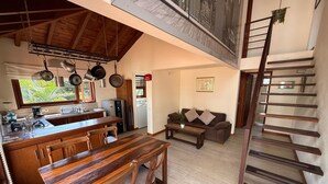 Una cocina amplia con armarios de madera, una mesa de comedor y una zona elevada con una escalera de madera.