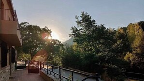 Un immeuble doté d’un balcon donnant sur une rivière et des arbres.