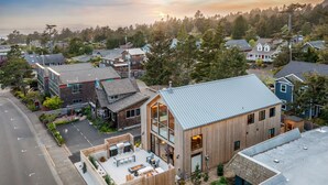 A modern house with a spacious patio, large windows, and a view of the surrounding neighborhood.