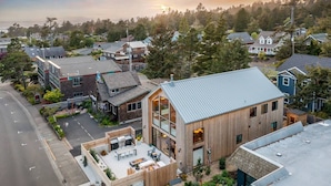 A modern building with a sloped roof, large windows, and a patio area with outdoor seating.