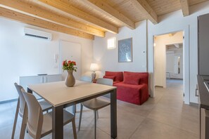 Un salon moderne avec une table à manger, des chaises, un canapé rouge, un vase de fleurs et un tableau accroché au mur.
