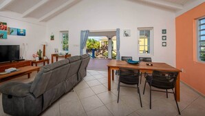 Un salon comprenant un canapé, un téléviseur et un coin repas avec des chaises et une table.