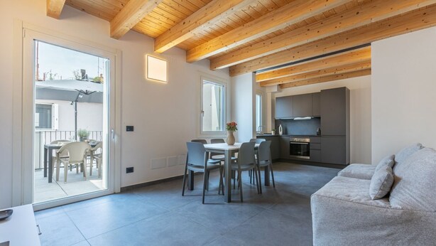 A modern interior with a dining area, kitchen, and a sofa. - GuestHost - Le Agavi - Lovely Flat X6 with Terrace (Ferrara)