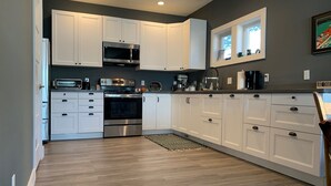 Una cocina moderna con armarios blancos, electrodomésticos de acero inoxidable y una ventana sobre el fregadero.