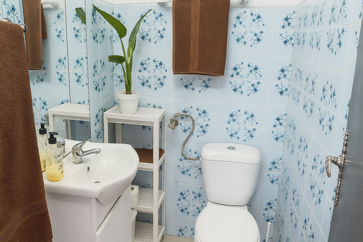 A bathroom with a toilet, sink, and a potted plant.