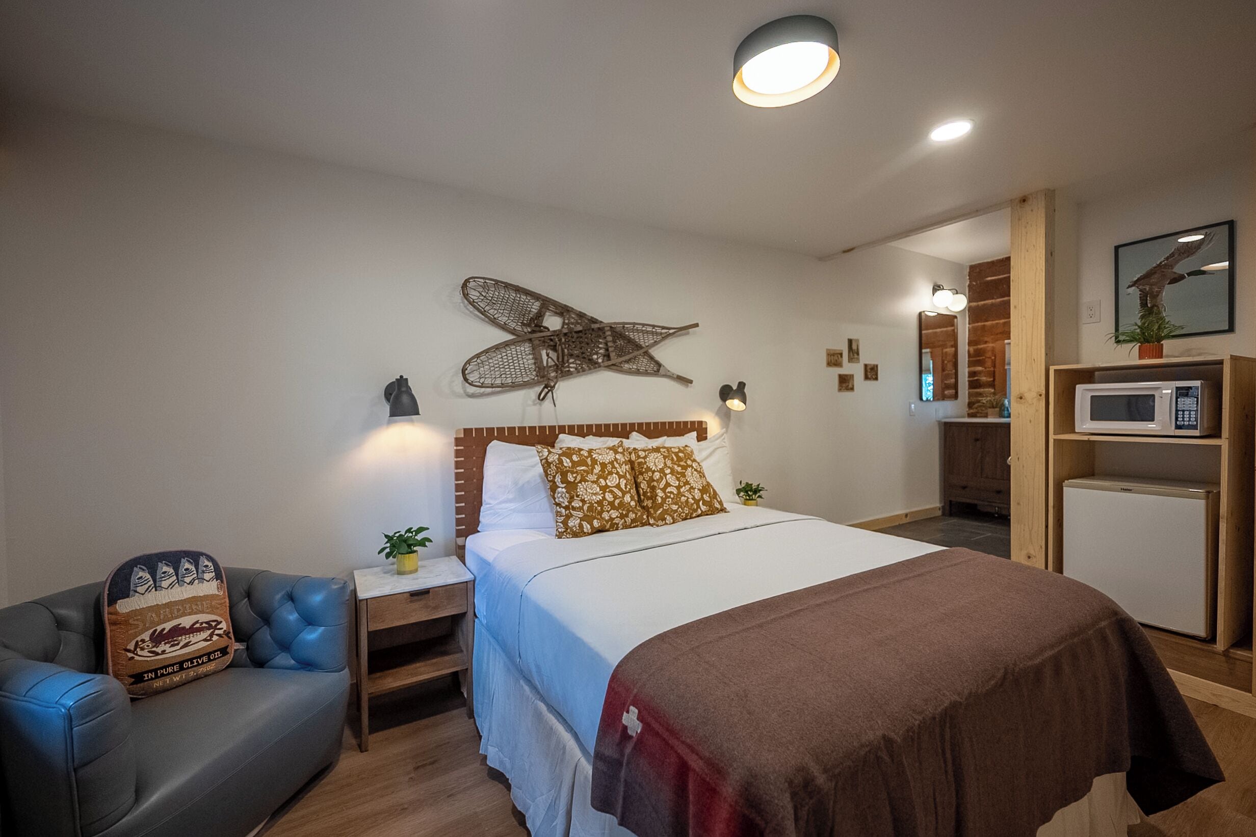 Ein Schlafzimmer mit Bett, Nachttischen, einem Schminktisch, einem Schrank, einer Mikrowelle und einer kleinen Pflanze.