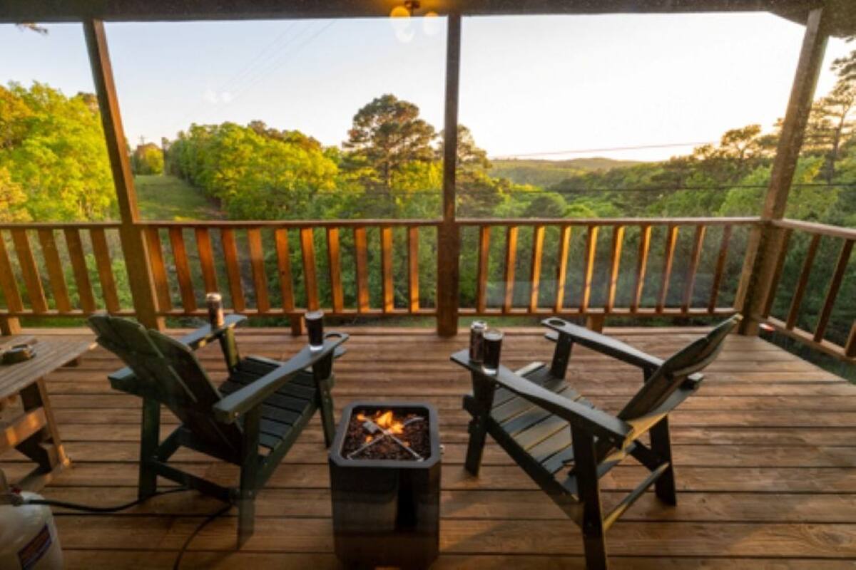 A wooden deck with a fire pit, two chairs, and a table.