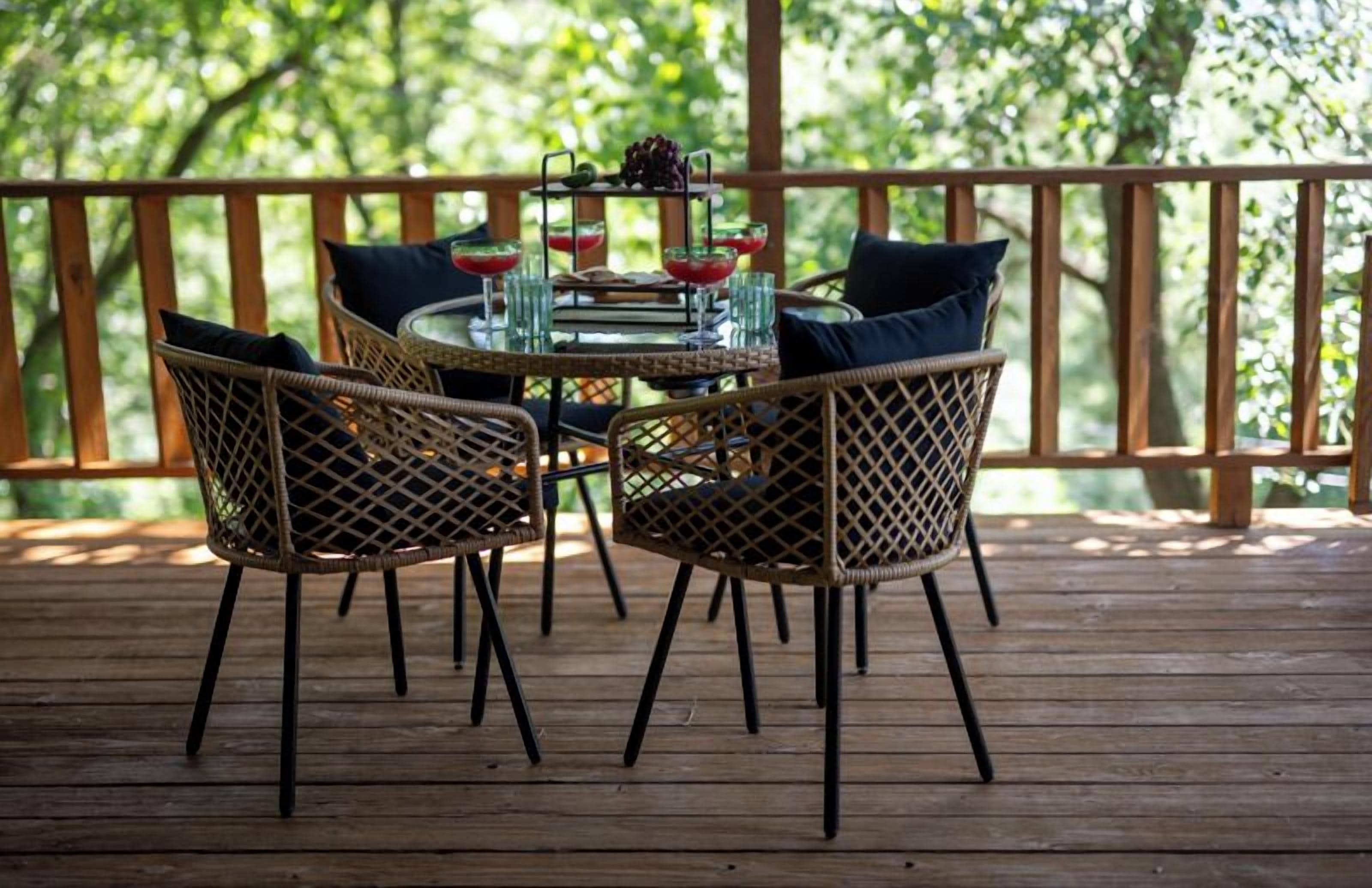 A wooden deck with wicker chairs and a glass table set for dining.