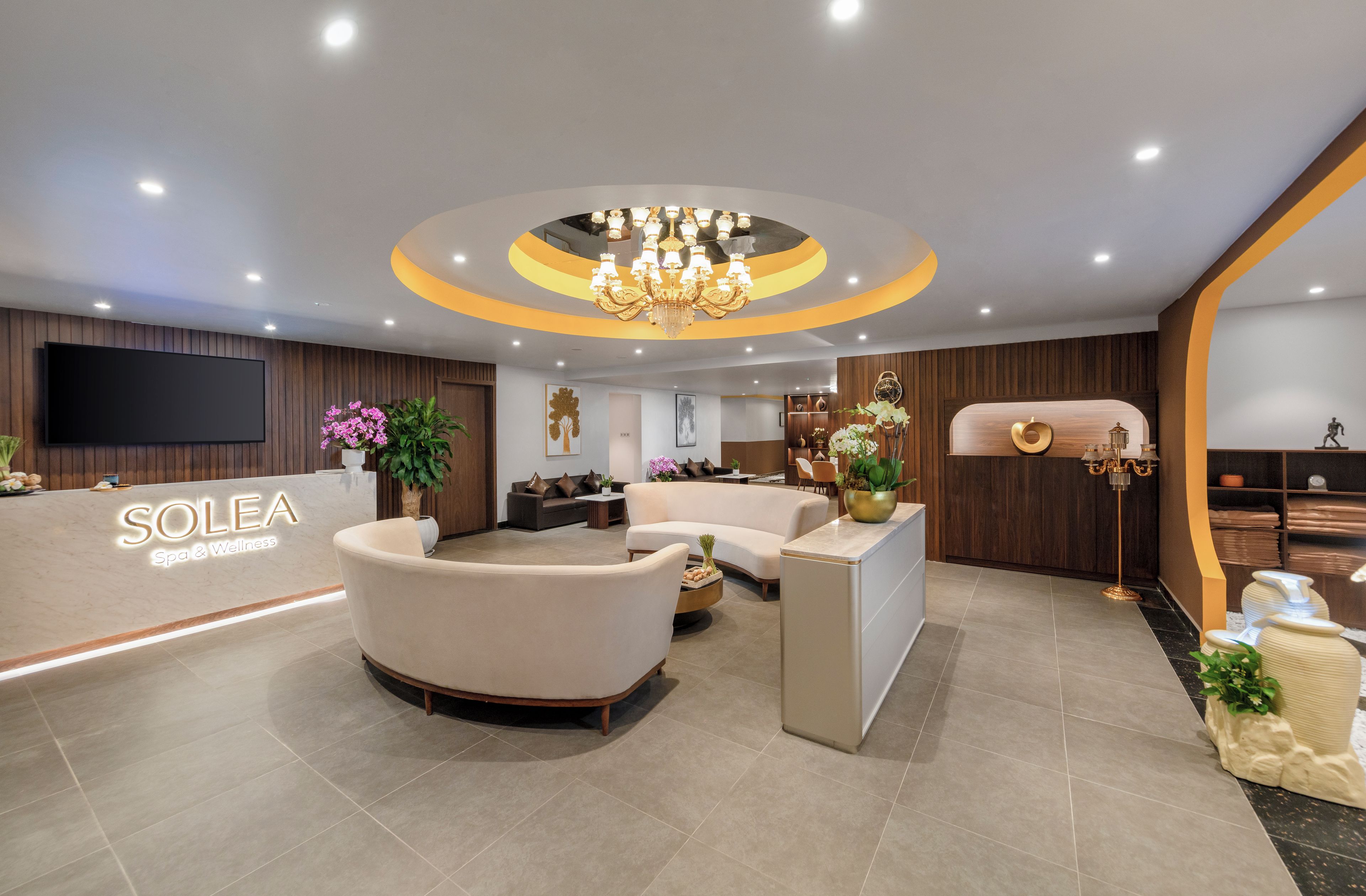A modern reception area with a sofa, a reception desk, and a chandelier.
